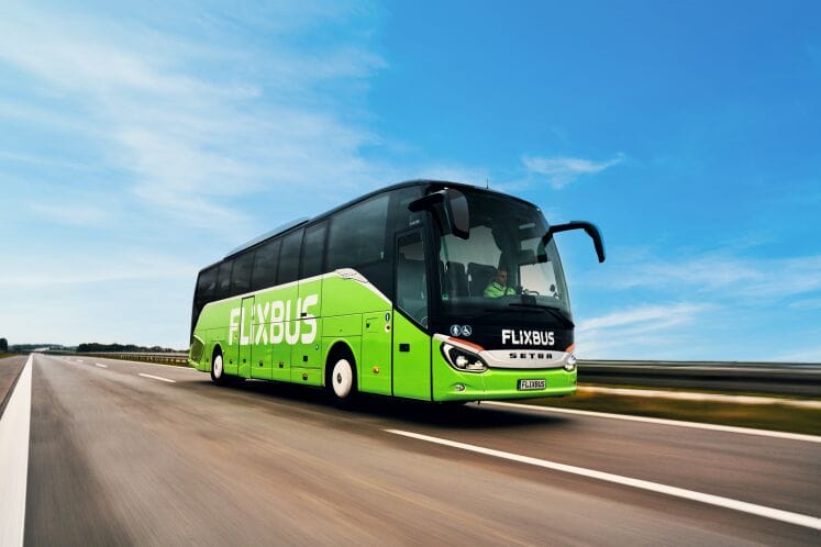 Autobús verde de FlixBus estacionado en una terminal, listo para iniciar un viaje económico entre ciudades de México con pasajeros jóvenes y mochilas.
