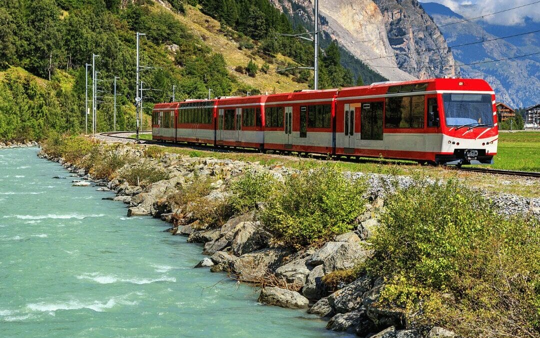 Tren Bernina Express recorriendo los Alpes suizos junto a un río turquesa